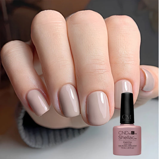 Hand with beige nail polish holding a CND Shellac Field Fox gel polish bottle.