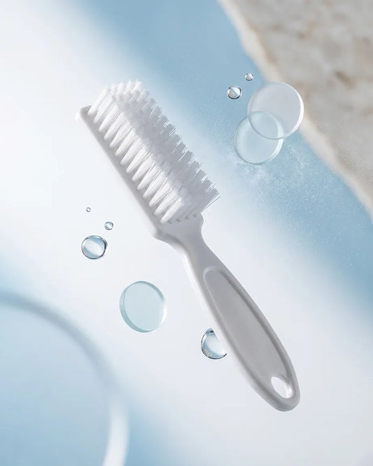 Cleaning brush with water droplets on a light blue background