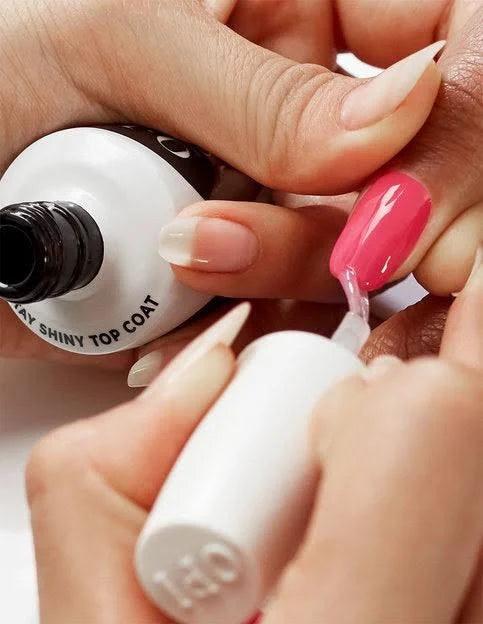 Person applying OPI top coat polish to another person's fingernail with a bottle of nail polish.
