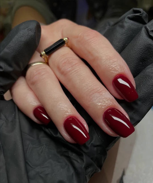Full manicure in DND DC Wineberry #061 on a hand, highlighting the sultry wine red color on all nails.