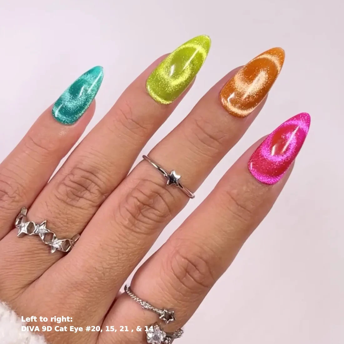 A close-up of a hand displaying four long, almond-shaped stiletto nails in vibrant, shimmering colors: teal, lime green, metallic gold, and hot pink. Each nail features a glossy cat-eye swirl pattern.