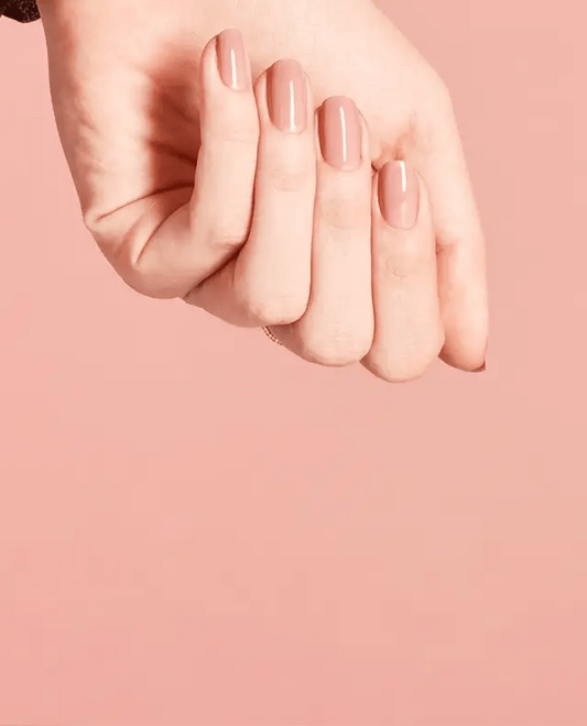 Manicured hand holding OPI F16 nude pink gel polish bottle showing the neutral finish