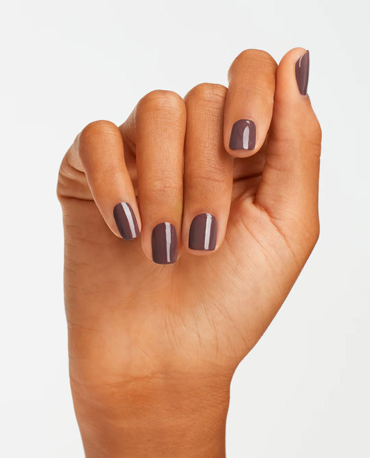 manicured Hand with OPI GelColor You Don’t Know Jacques F15 gel polish dark purple nail polish on a light gray background