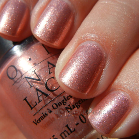 Tropical pink coral manicure with OPI Cozu-Melted In The Sun displayed in sunny vacation setting.