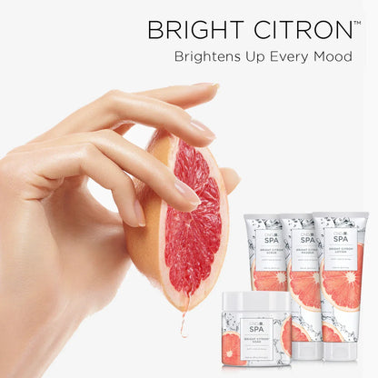 Hand holding a sliced grapefruit with skincare products labeled 'Bright Citron' on a white background