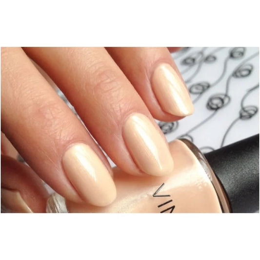 A close-up of a hand with glossy nude-beige manicured nails resting on a matching nail polish bottle, CND shellac Dandelion