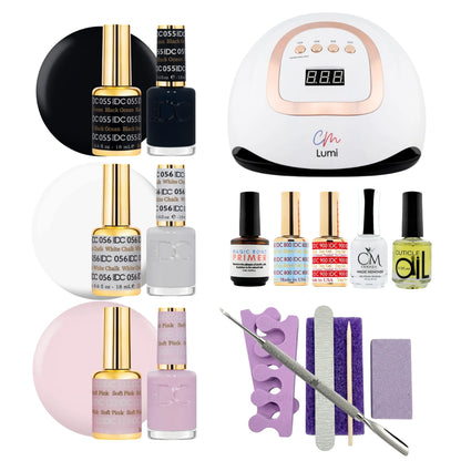 A nail polish starter kit and manicure set arranged on a white background, including a white UV lamp with a digital display, several nail polish bottles in black, white, pink, and yellow, a purple nail file tray, purple and lavender files, a metal cuticle tool, and other small accessories. Visible branding includes DC DND gel polish