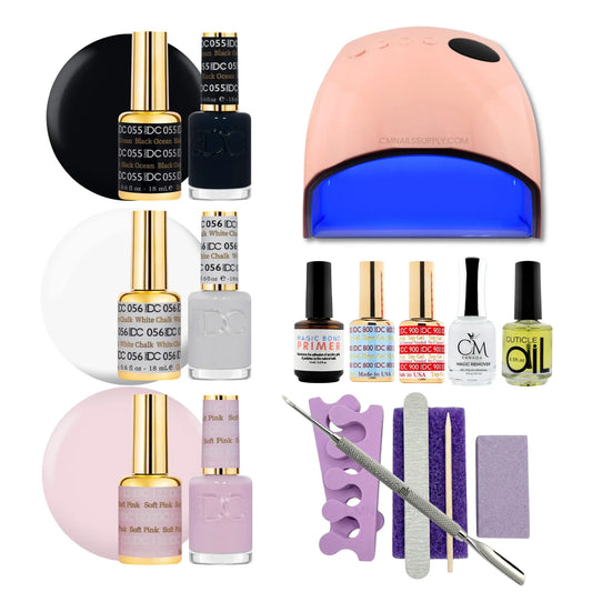 A DC gel polish manicure set arranged on a white background, including a UV nail lamp, several bottles of nail polish in black, white, pink, and gold, a purple nail file, a metal nail tool, and other small accessories.