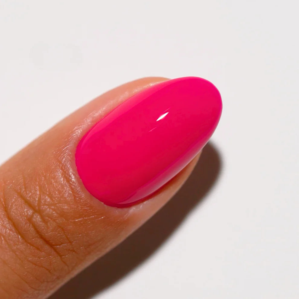 Close-up of a hand with a bright pink nail on a light background DND Kandy #711 gel polish nail lacquer duo