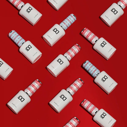 Multiple white bottles of DND gel nail polish with silver caps are arranged diagonally on a solid red background. Some bottles show the red-and-white 'DND' patterned cap, while others show the blue-and-white 'DND' patterned cap.