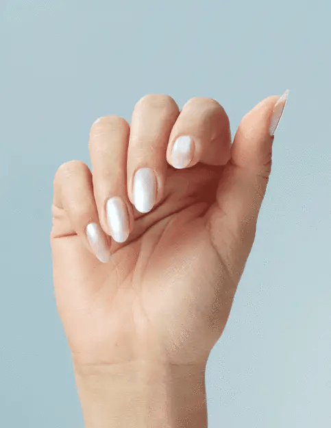 Hand with neatly manicured nails against a light blue background