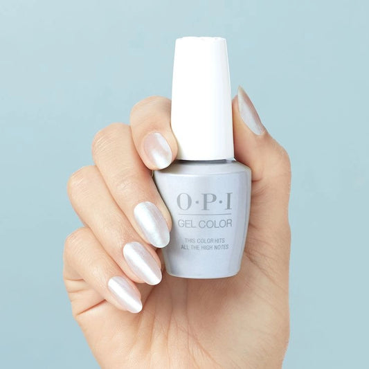 Hand holding a bottle of OPI this color hits all the high notes gel color nail polish against a light blue background