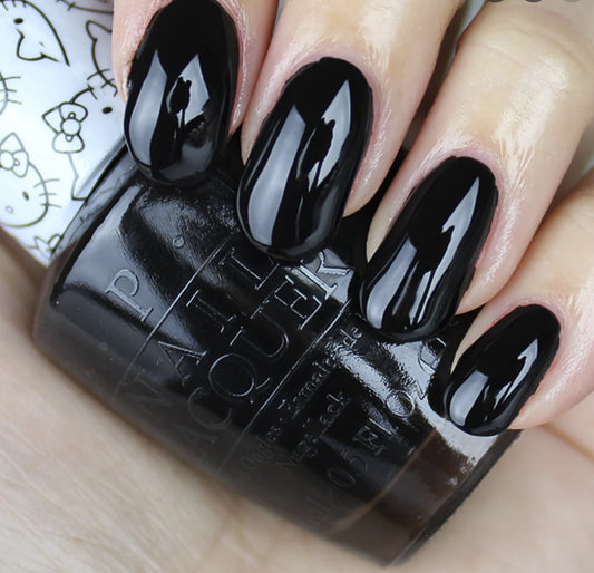 Black nail polish bottle with nails painted black on a light background