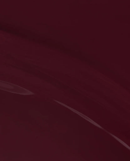 A close-up of a glossy deep burgundy or maroon surface with soft light reflections.