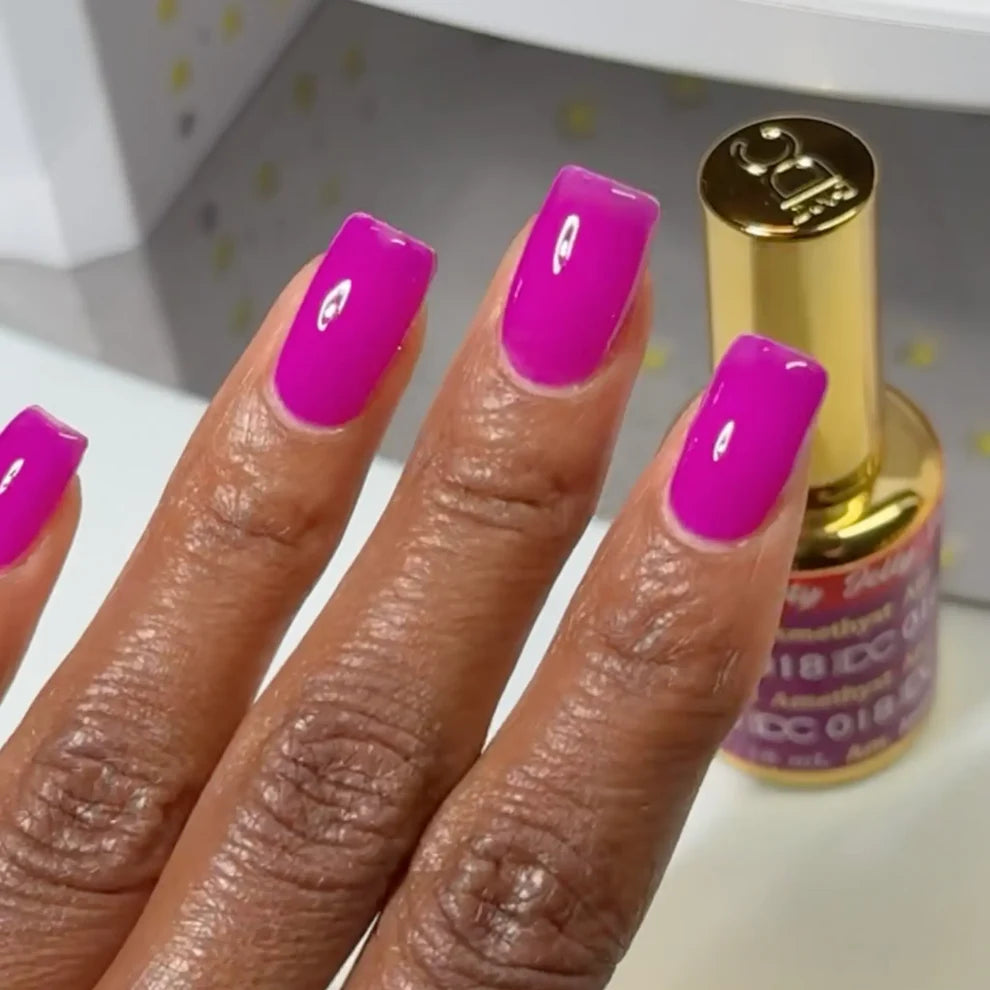 Manicured hand with dark skin tone wearing DC Jelly 018 Amethyst jelly gel polish in a magenta purple finish