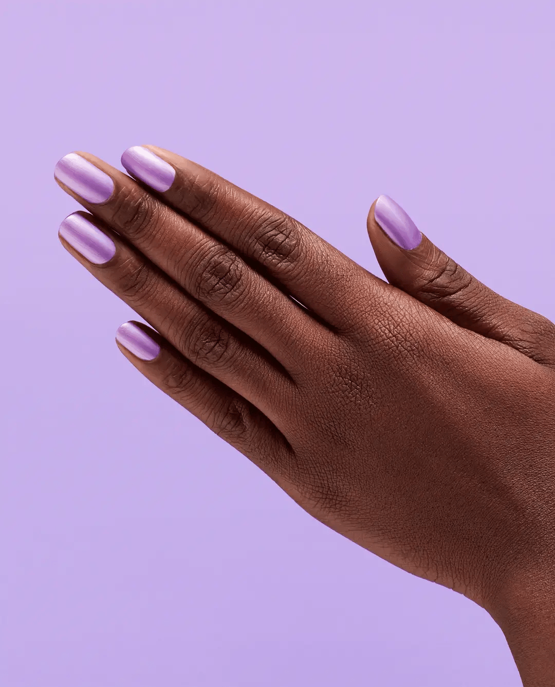Hand with purple nail polish on a purple background