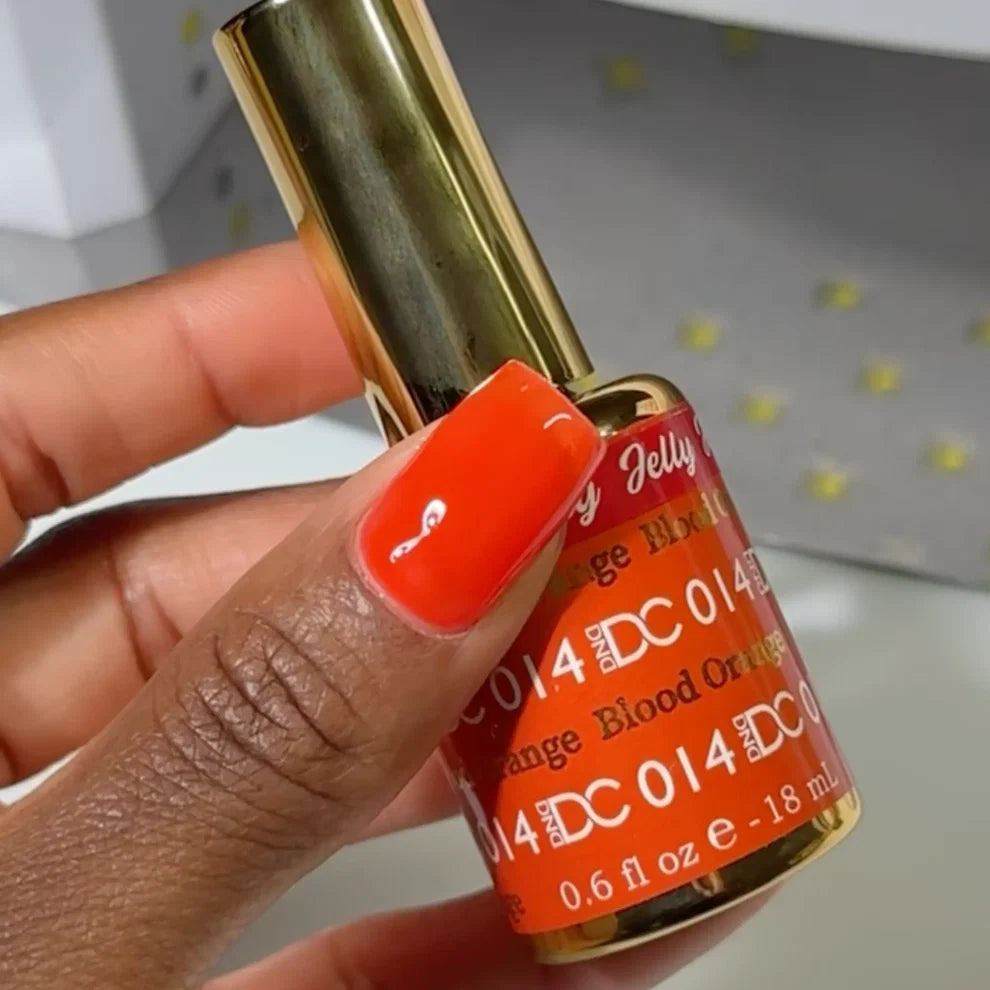 Manicured hand with dark skin tone wearing DC Jelly 014 Blood Orange jelly gel polish in a deep neon orange finish