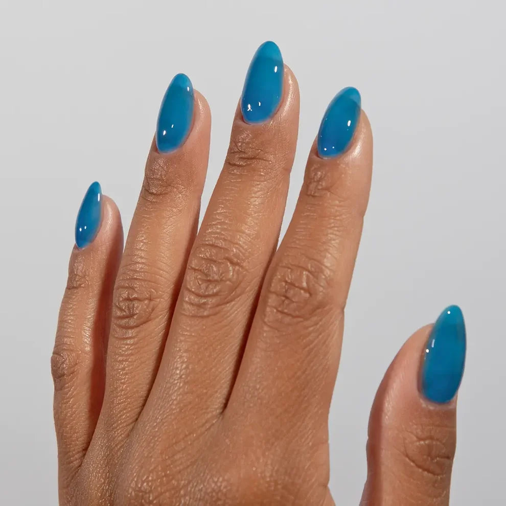 Manicured hand wearing DC Jelly 023 Capri jelly gel polish to show the poolside azure blue finish in natural light