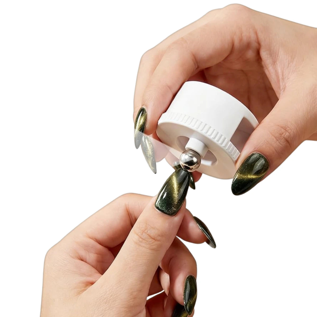 A close-up of hands demonstrating a magnetic cat eye tool. The hands have metallic green nails, and the white magnetic tool is being used to shape a nail tip on a white background.