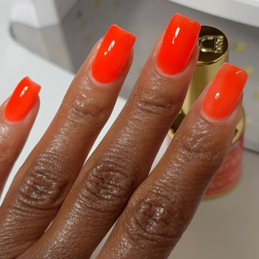 Manicured hand wearing DC Jelly 07 Citrus jelly gel polish to show the tangy fiery orange finish in natural light on dark skin