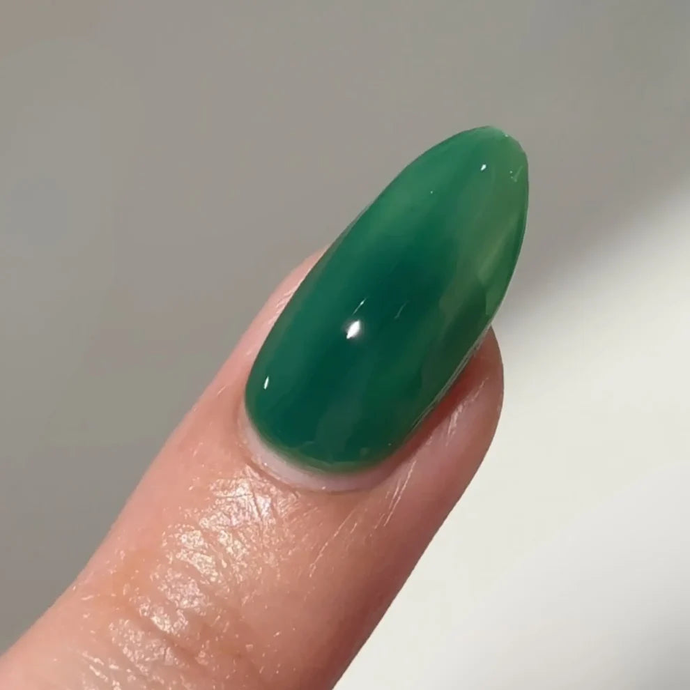 Close up of DC Jelly 05 Kelly jelly nail polish applied on a single finger showing the glossy green finish