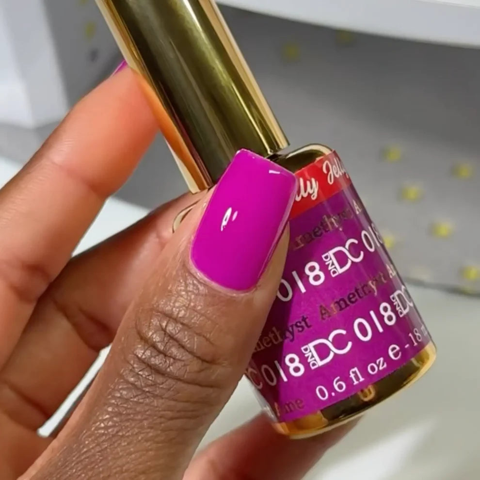Deep skin tone manicured hand showing DC Jelly 018 Amethyst jelly gel polish with a royal purple creamy glow