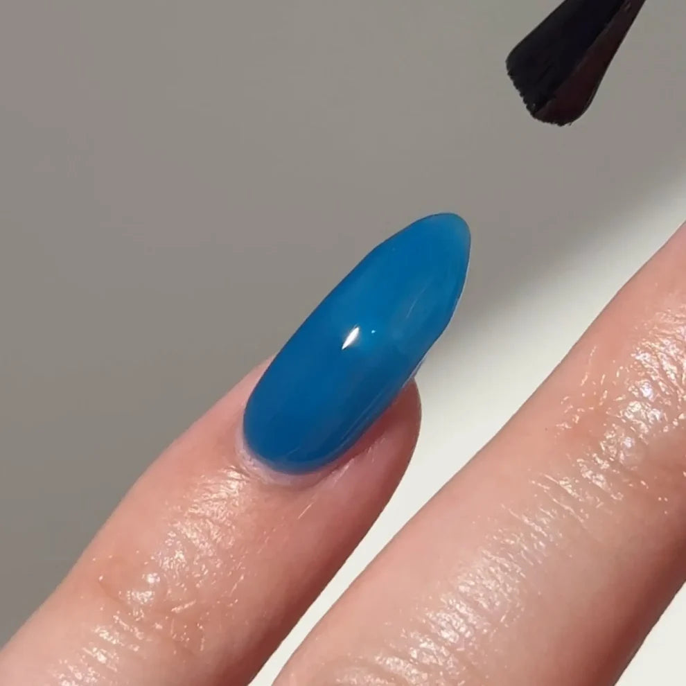 Fair skin manicured hand showing DC Jelly 023 Capri jelly gel polish with a vacation ready azure glow