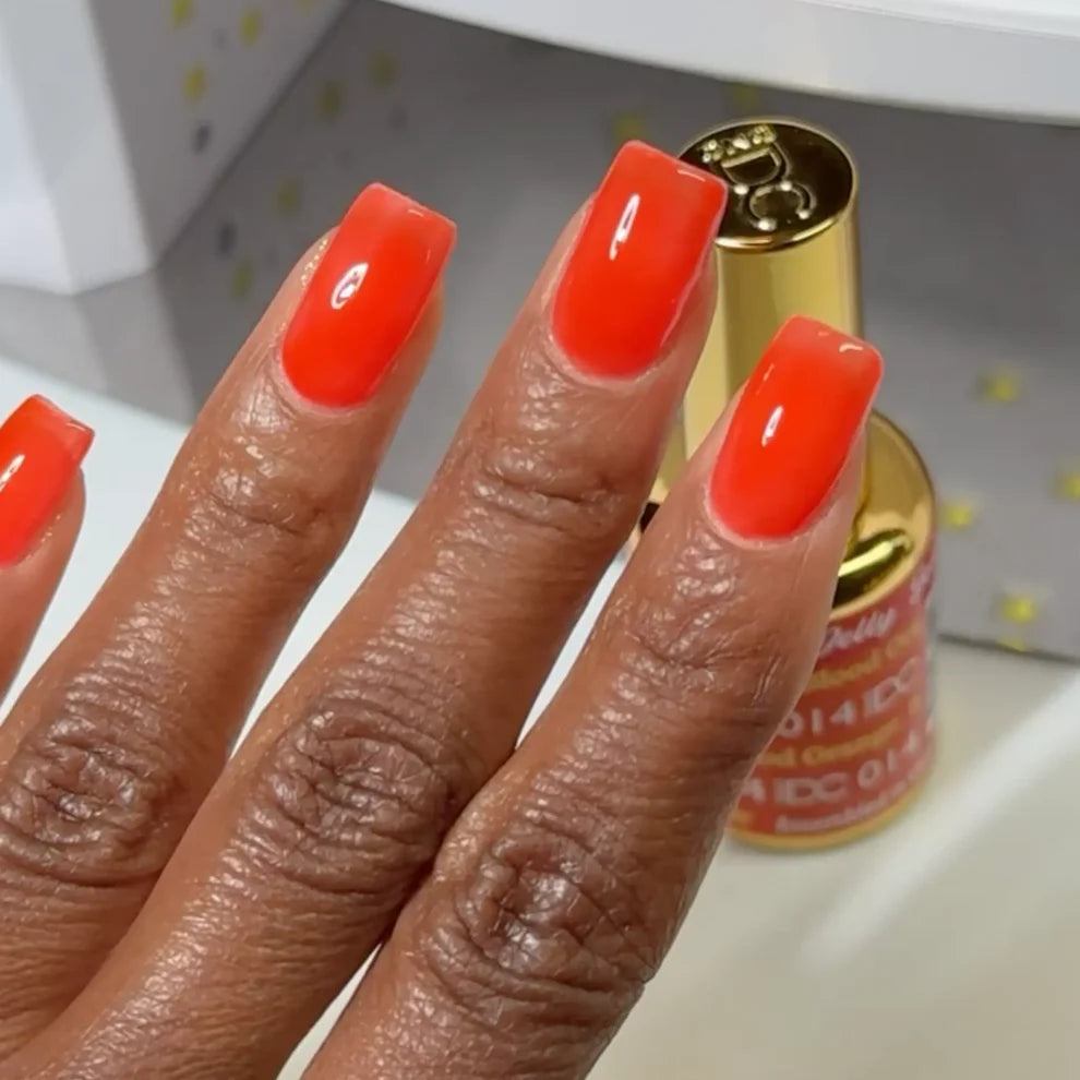 Manicured hand with DC Jelly 014 Blood Orange jelly gel polish applied to show the finished salon style manicure
