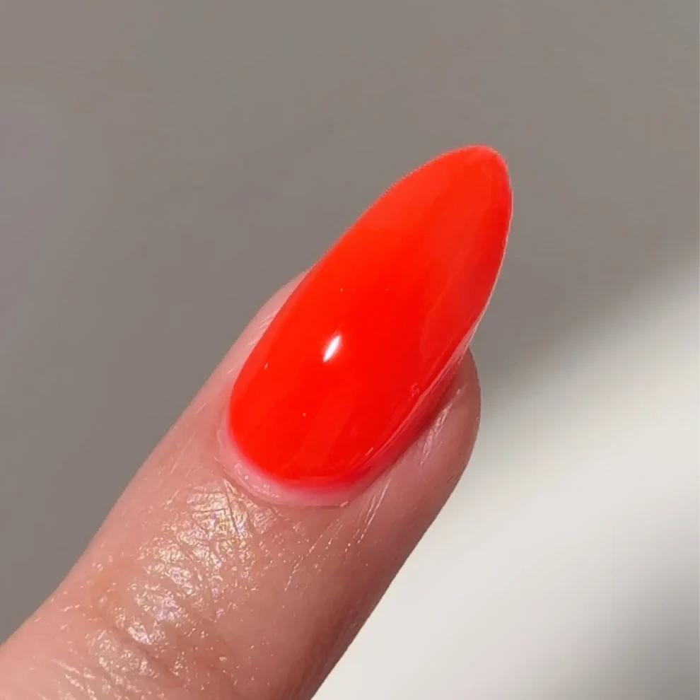 Manicured hand with DC Jelly 013 Tiger Blood jelly gel polish applied to show the finished salon style manicure