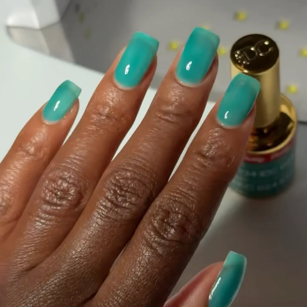 Deep skin tone manicured hand showing DC Jelly 024 Jade jelly gel polish with a crystal clear turquoise glow