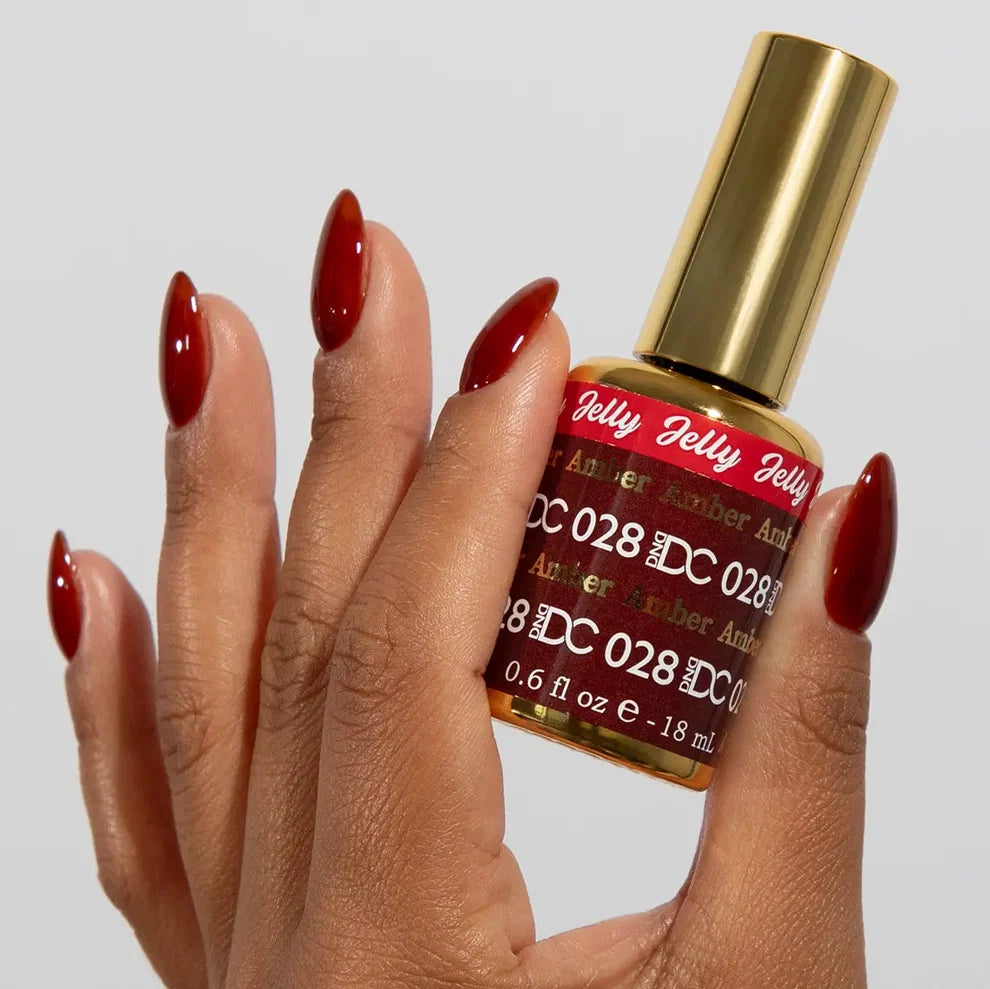 DC manicured hand holding the jelly nail polish bottle for Amber 028, showcasing the golden brown color on the nails