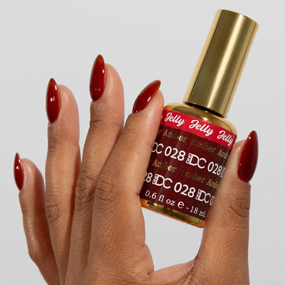 DC manicured hand holding the jelly nail polish bottle for Amber 028, showcasing the golden brown color on the nails