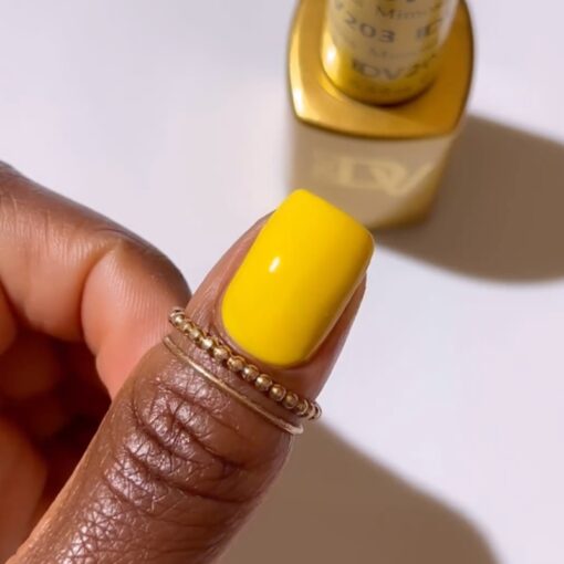 Close up manicured finger wearing DIVA #203 Mimosa soft canary yellow gel polish with glossy finish