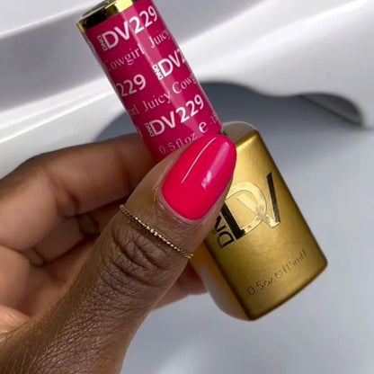 Hand holding a pink lip gloss with gold cap, brand 'DV229' visible
