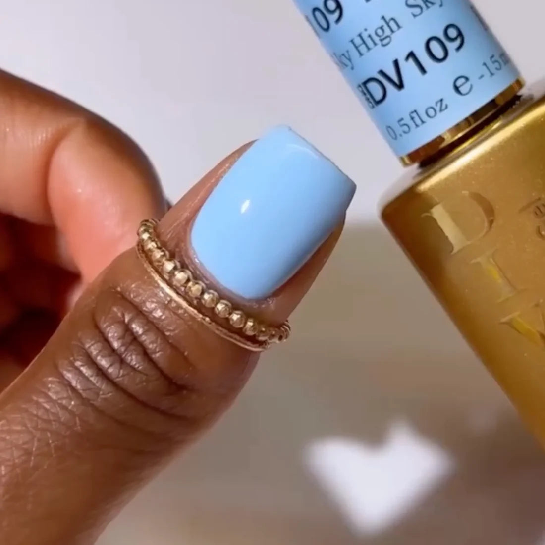 Hand showing finished manicure in DIVA Sky High bright sky blue gel nail polish