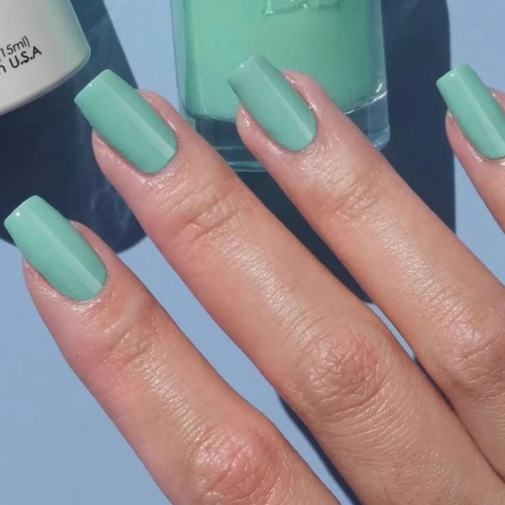 Mint green manicure featuring DND Air Of Mint #427 while holding the matching Gel & Lacquer Duo.