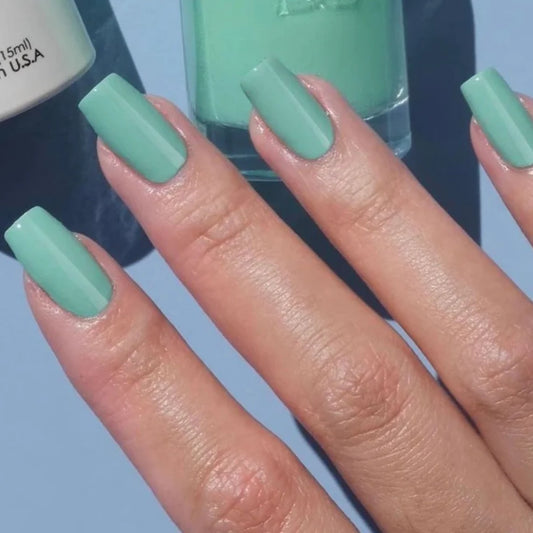 Mint green manicure featuring DND Air Of Mint #427 while holding the matching Gel & Lacquer Duo.