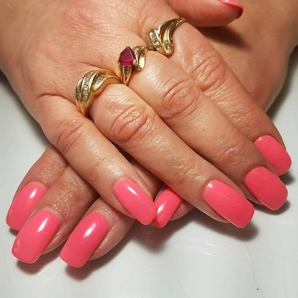 Hand wearing DND Coral Reef #556 gel polish, showing the bright neon coral tone on the nails