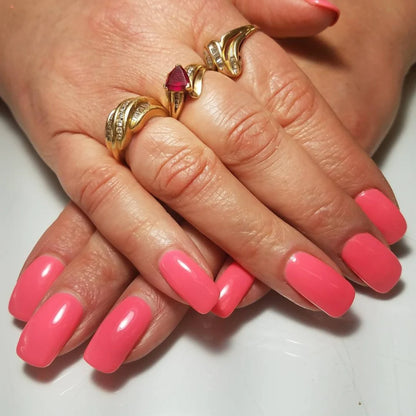 Hand wearing DND Coral Reef #556 gel polish, showing the bright neon coral tone on the nails