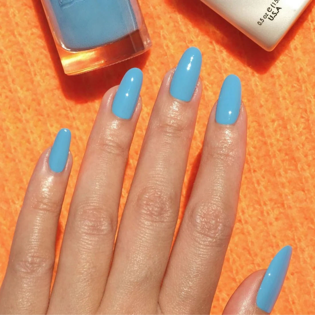 Manicured hand wearing DND DC Blue Lake 530 gel polish with a glossy sky blue finish.