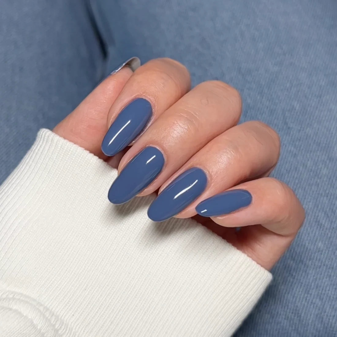 Close up of a hand wearing a DND DC Goodie Bag #321 manicure with a glossy denim blue finish