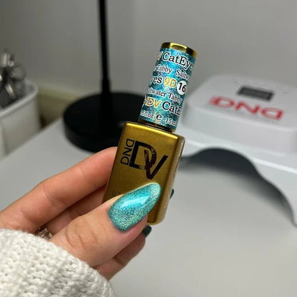 Hand with an aquamarine cat eye manicure holding the DND Diva Cat Eye Gel Polish #16 Saltwater Tabby bottle.