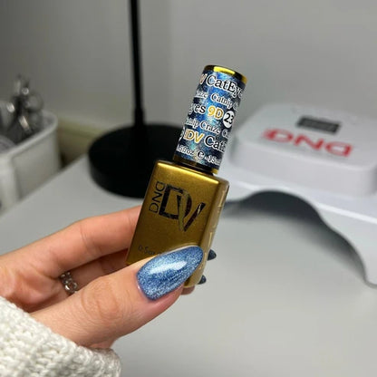 Hand with a velvety blue cat eye manicure holding the DND Diva Cat Eye Gel Polish #23 Catnip Craze bottle.