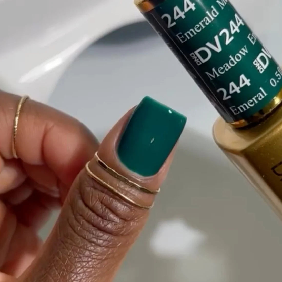 Manicured hand with deep forest green gel nails using DND DIVA Emerald Meadow polish