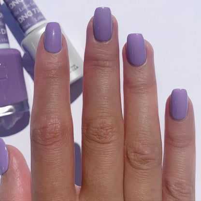A close-up of a hand with neatly manicured nails painted in DND gel lollie 737 a light lavender purple shade, with a bottle of nail polish visible in the blurred background.