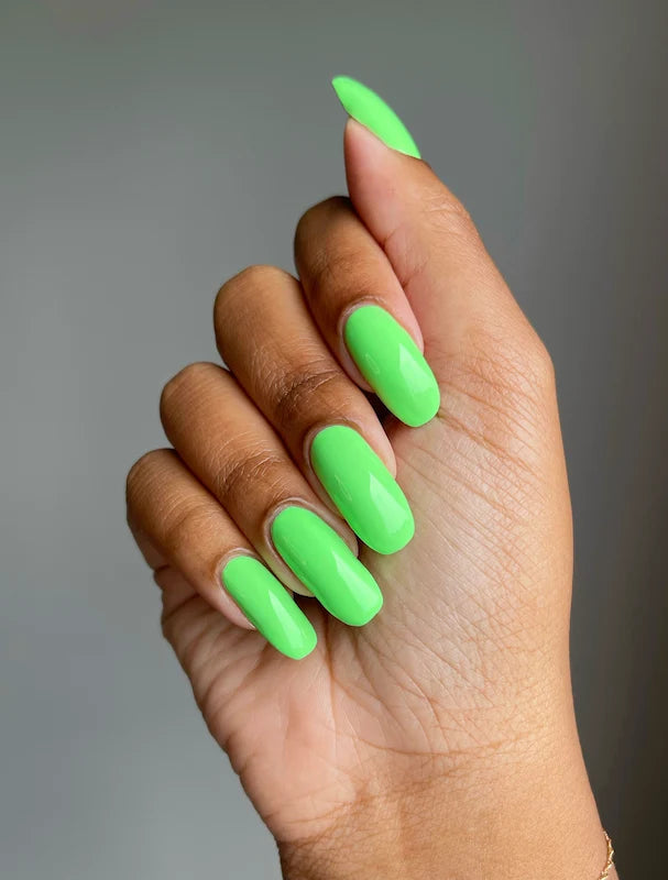 Hand wearing DND Green Forest #568 gel polish, showing the vivid neon green tone on the nails