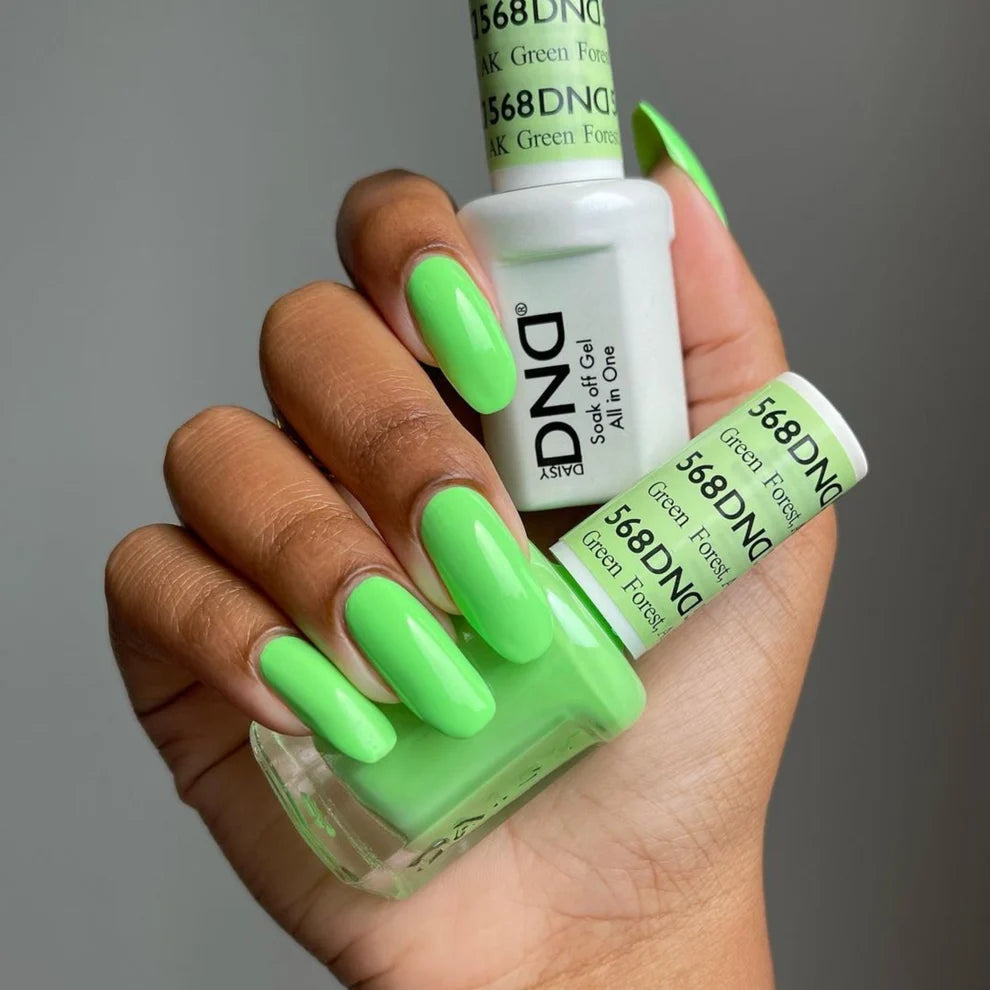 Finger nail painted with DND Green Forest #568, a shockingly bright neon green gel polish holding the DND gel polish bottles