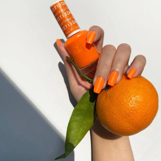DND Orange Sherbet #713 orange manicure holding a fresh orange