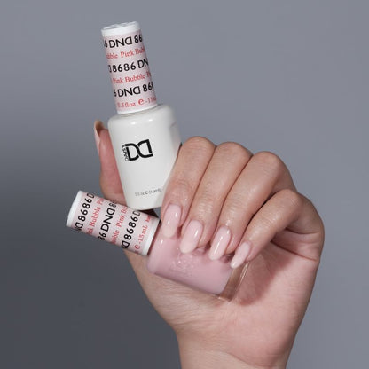Manicured hand holding DND Pink Bubble #8686 gel and lacquer duo set bottle collection