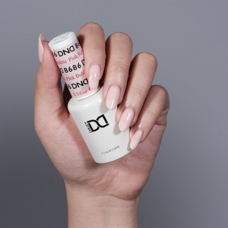 Manicured hand holding DND Pink Bubble #8686 gel polish bottle close up view
